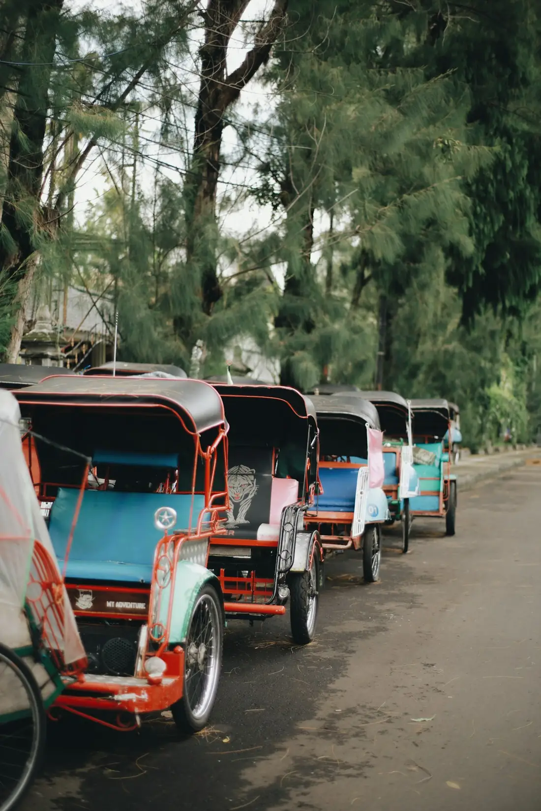 Barisan becak merah khas Indonesia di tepi jalan